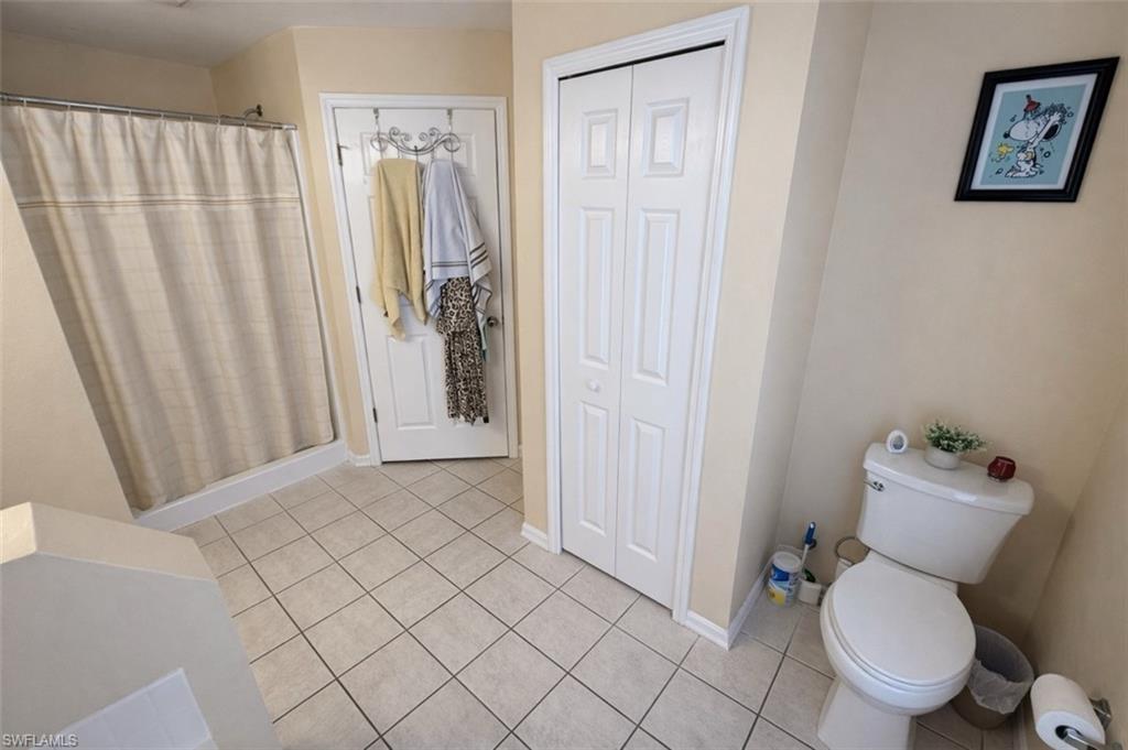 Bathroom featuring a closet, a shower stall, and light tile patterned floors