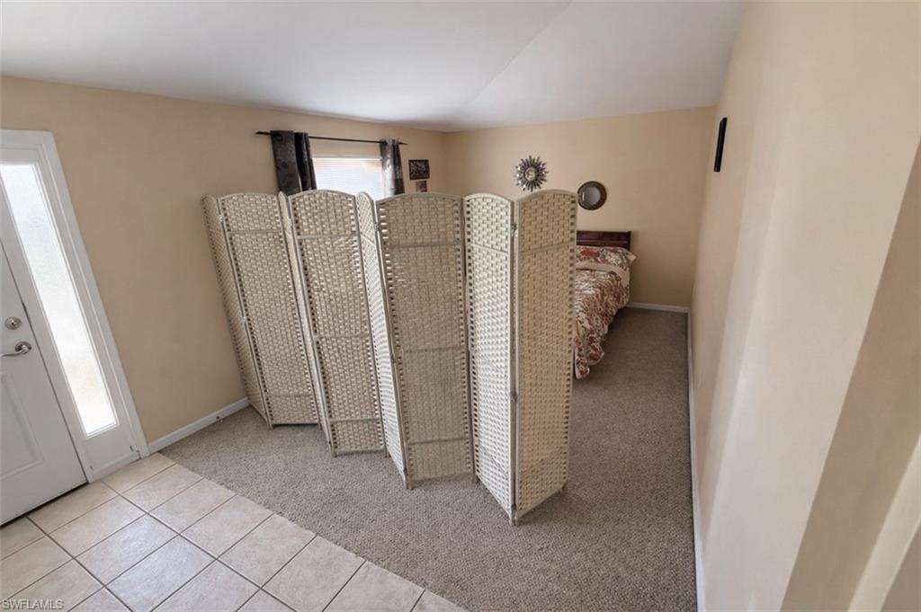 Bedroom with light carpet, light tile patterned floors, and vaulted ceiling