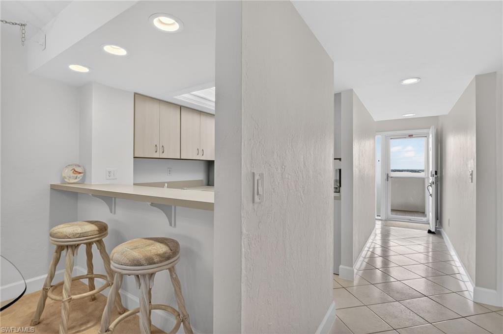 Hallway featuring recessed lighting, light tile patterned floors, and a textured wall