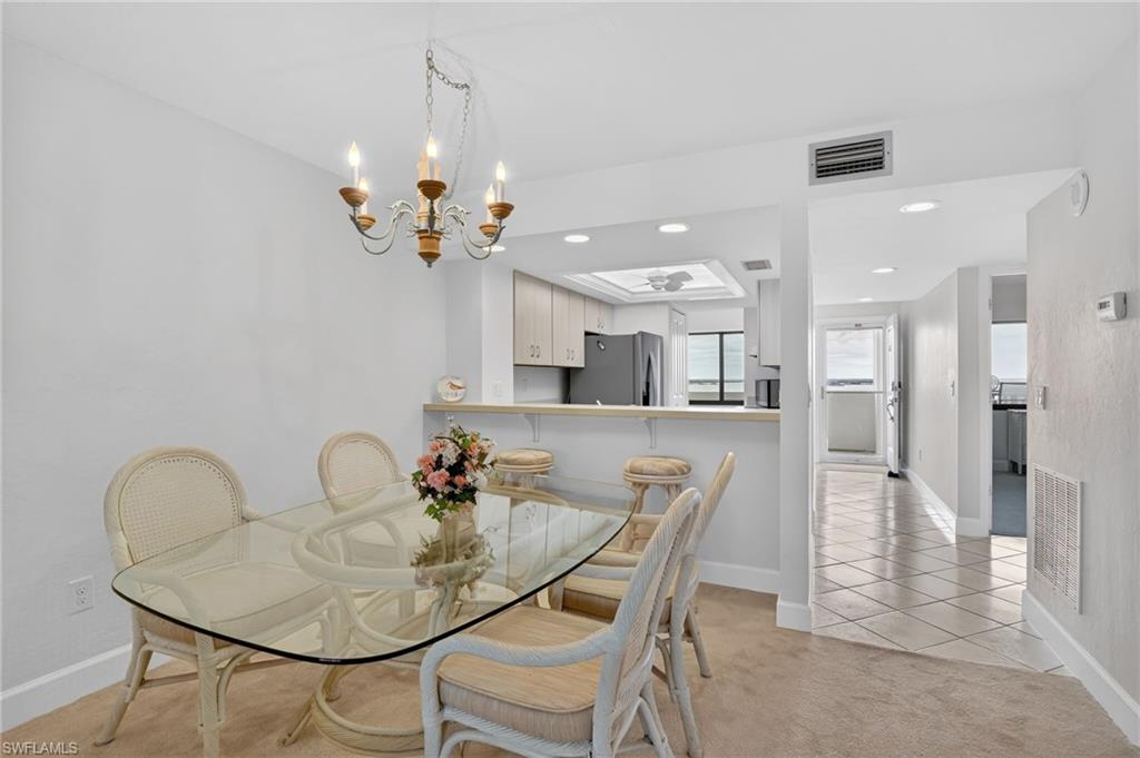 Dining area with light tile patterned floors, light carpet, and suspended lighting