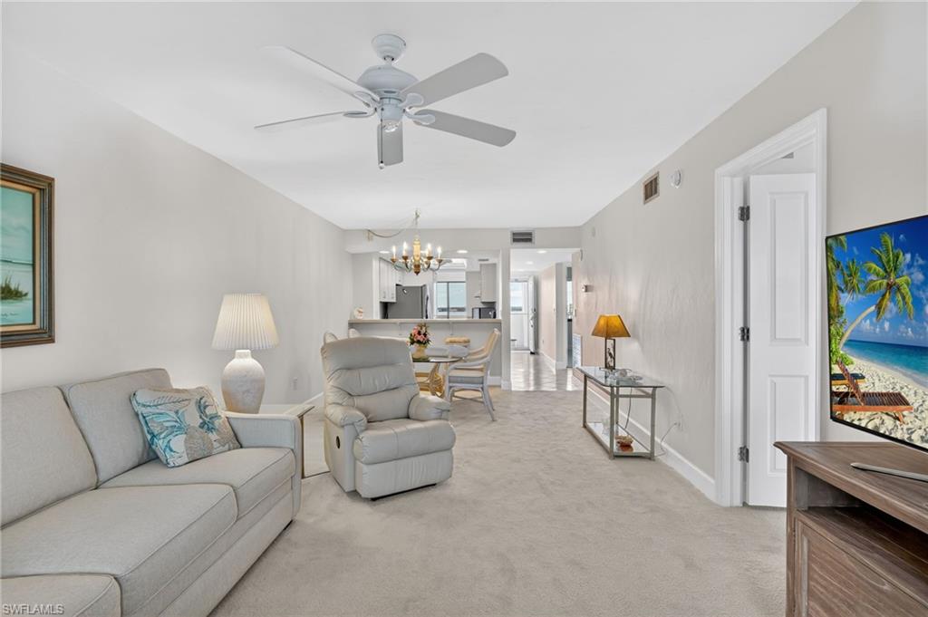 Living room with hanging lights, light carpet, and a ceiling fan
