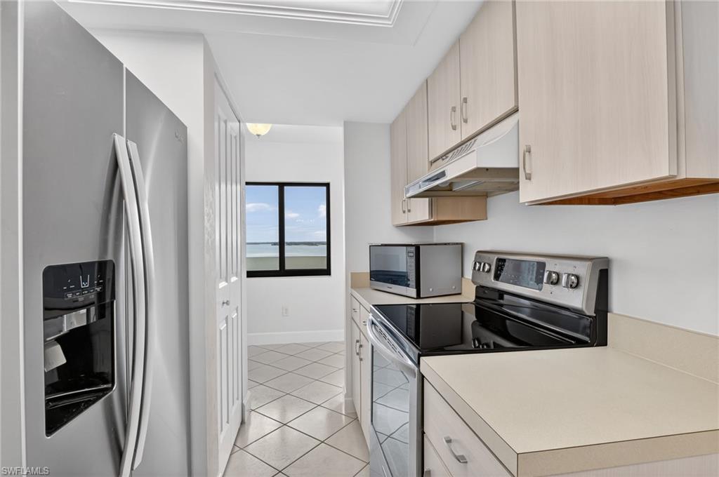 Kitchen with stainless steel appliances, light countertops, and light tile patterned flooring