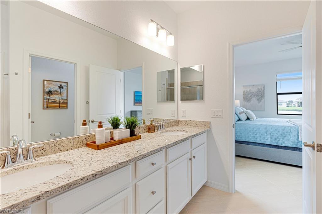 Bathroom with double vanity, connected bathroom, and light tile patterned flooring