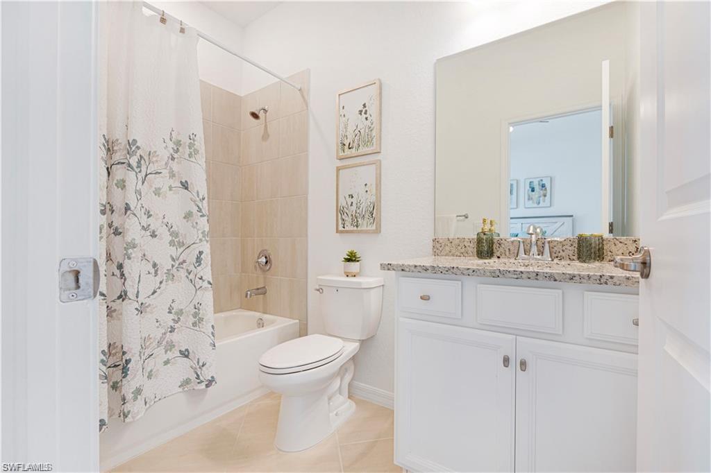 Full bath featuring vanity, shower / tub combo with curtain, and light tile patterned flooring