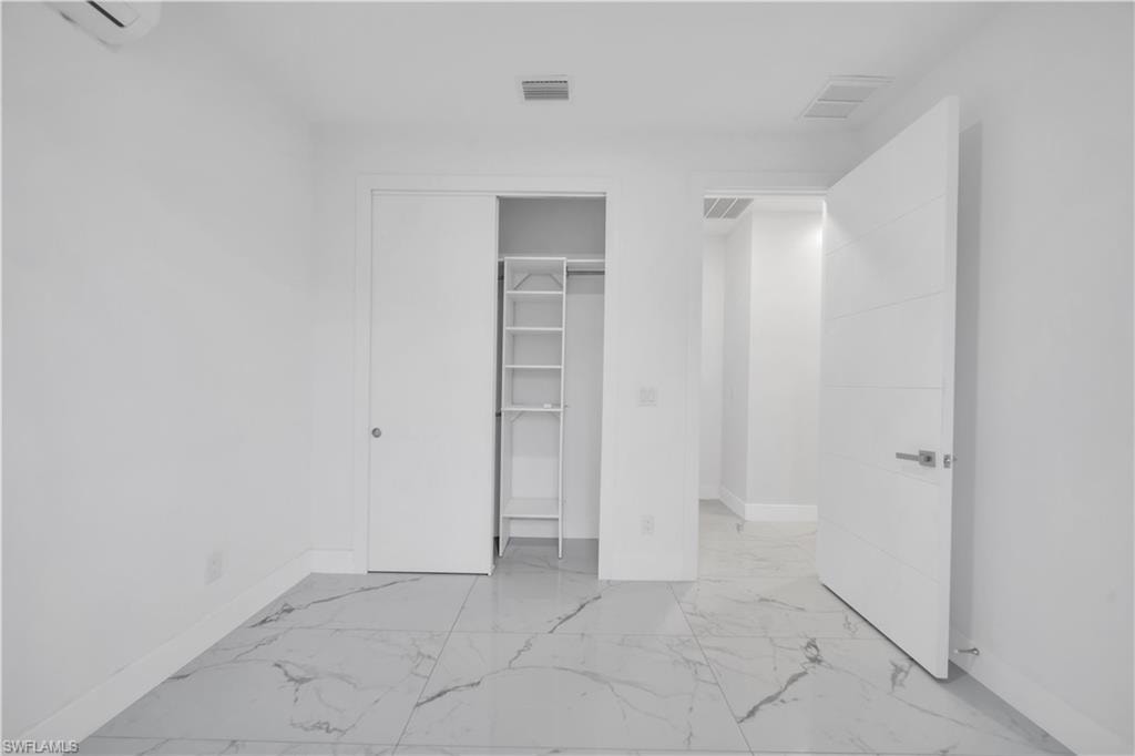 Unfurnished bedroom with light marble finish flooring and a closet