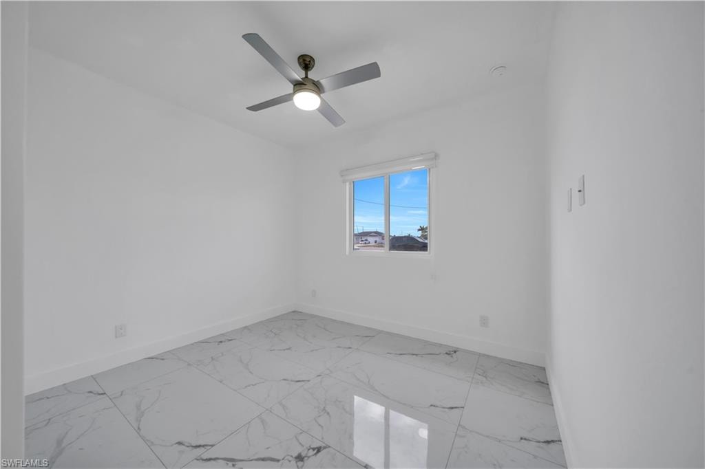 Spare room with light marble finish flooring and ceiling fan