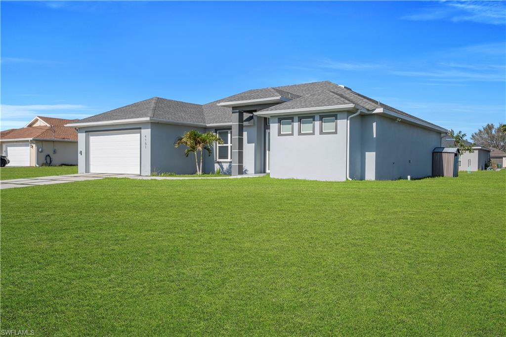 Prairie-style home with a front lawn, stucco siding, a shingled roof, and an attached garage
