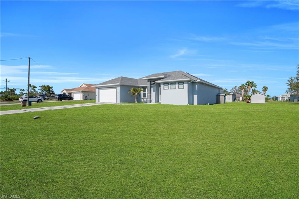 Prairie-style home featuring a front lawn, stucco siding, concrete driveway, a garage, and a residential view
