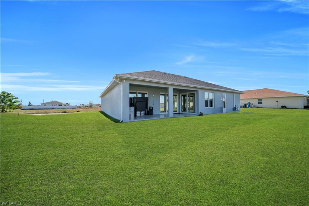 Rear view of house featuring a yard, a patio area, and stucco siding