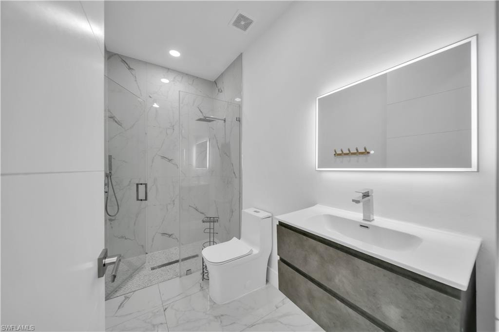 Full bathroom featuring vanity, a marble finish shower, recessed lighting, and light marble finish flooring