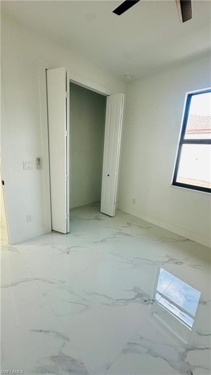 Unfurnished bedroom featuring a closet, ceiling fan, and light marble finish flooring