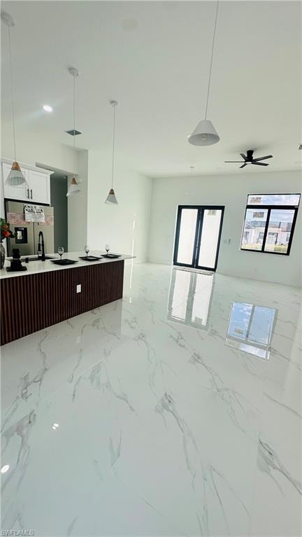 Kitchen with pendant lighting, stainless steel fridge with ice dispenser, open floor plan, and white cabinets