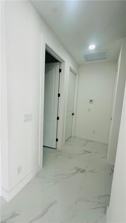 Hallway featuring attic access and baseboards
