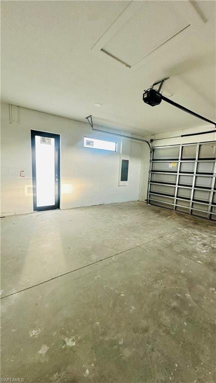 Garage with concrete block wall, electric panel, and a garage door opener