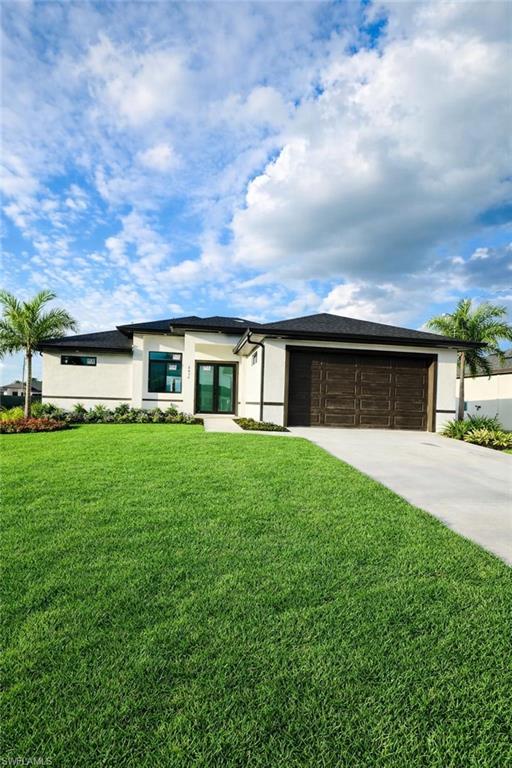 Prairie-style house featuring a front lawn, reel color grass stucco siding, and concrete driveway
