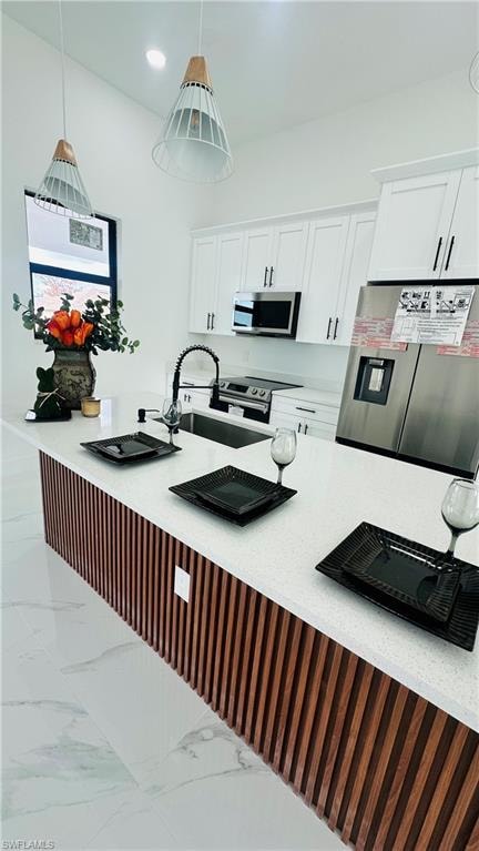 Kitchen with stainless steel appliances, white cabinetry, light stone countertops, hanging light fixtures, and a breakfast bar