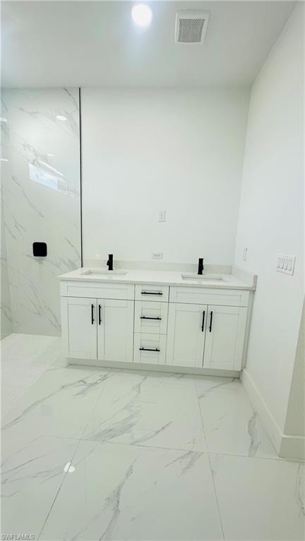 Bathroom with double vanity, light marble finish flooring, and recessed lighting