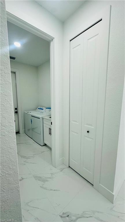 Laundry room with light marble finish flooring and washing machine and clothes dryer