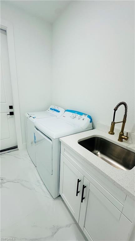 Laundry area featuring washer and clothes dryer, cabinet space, and light marble finish flooring