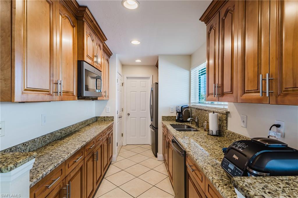 Kitchen featuring wood finish cabinets, stainless steel appliances, light stone countertops, and recessed lighting