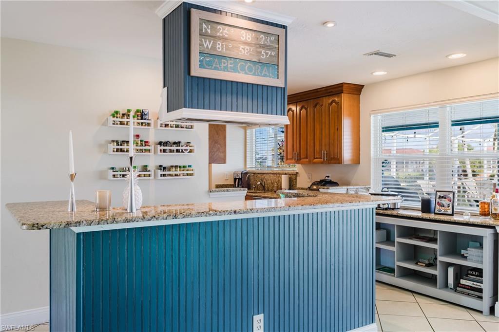 Kitchen featuring light stone countertops, open shelves, wood finish cabinets, recessed lighting, and a peninsula