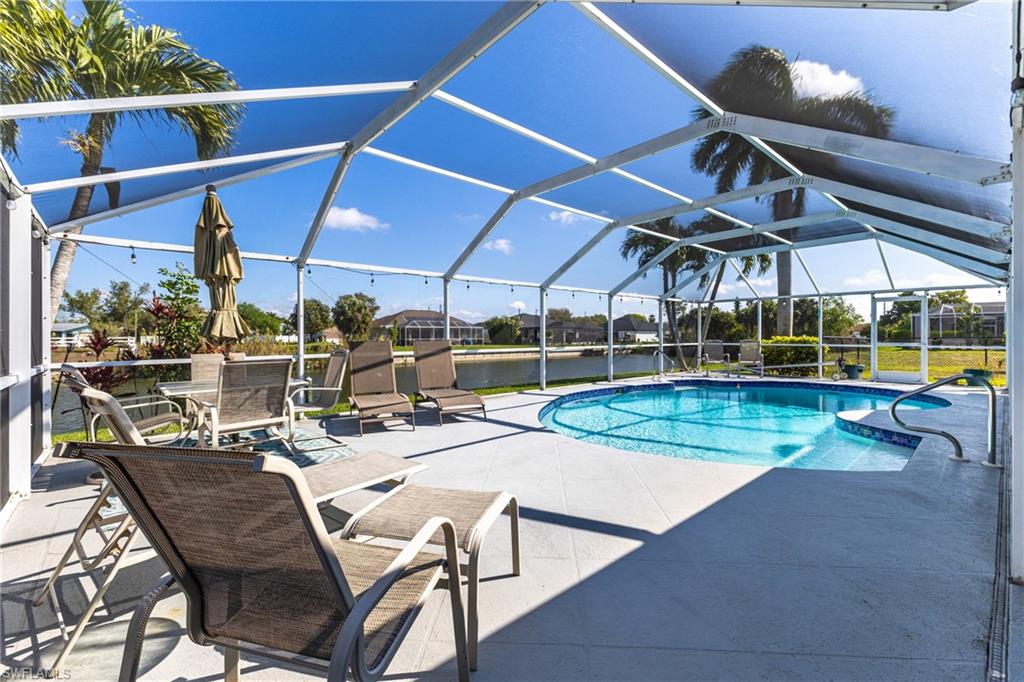 Swimming pool with a patio area, a sunroom, a lanai, a water view, and a residential view
