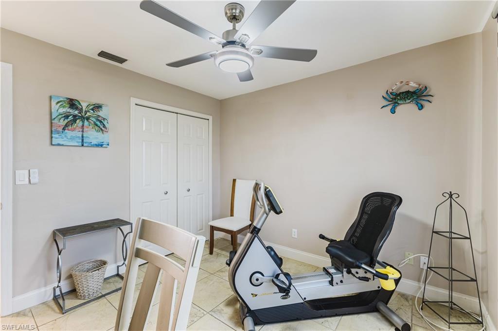Exercise room with ceiling fan and light tile patterned flooring