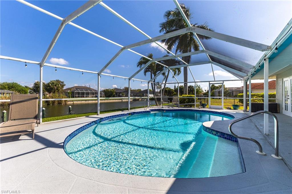 Swimming pool featuring a sunroom, glass enclosure, a patio, and a water view