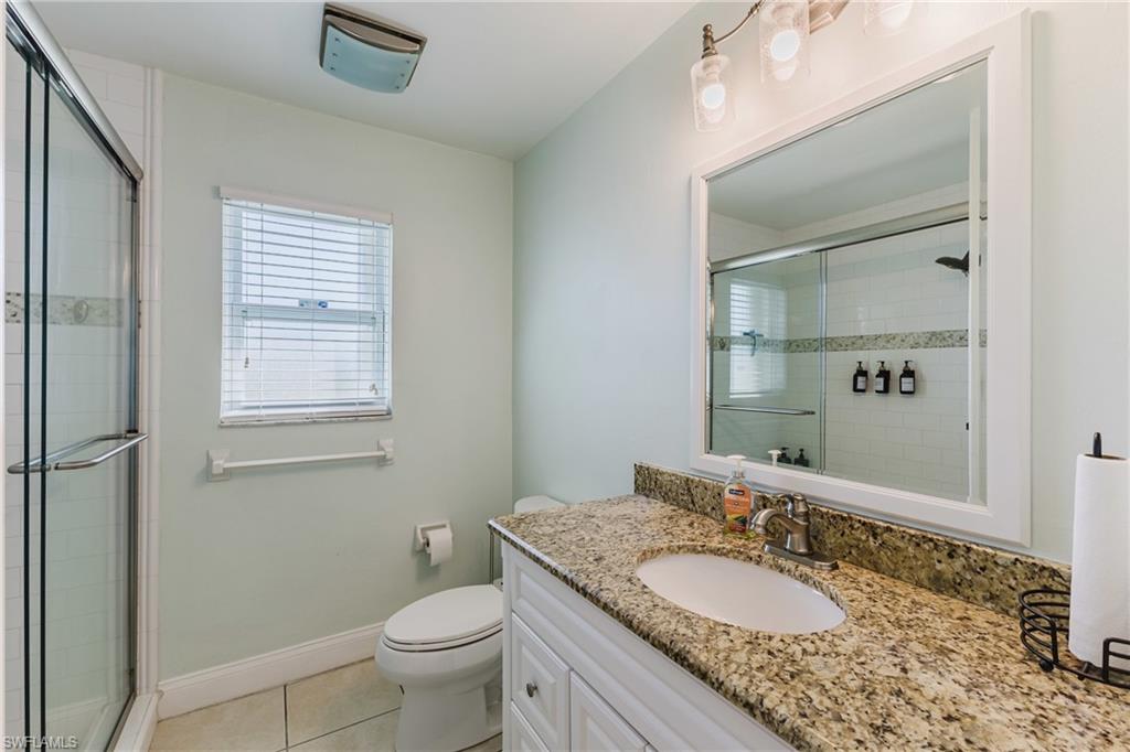 Bathroom with vanity, light tile patterned floors, and a shower stall