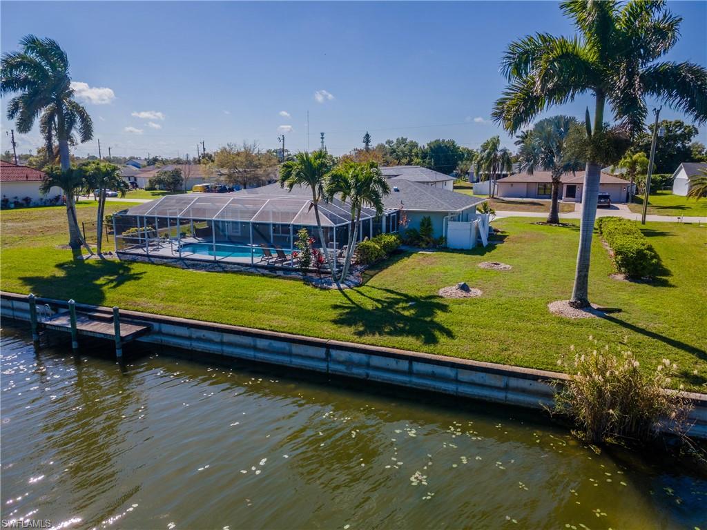 Back of property with a sunroom, a lanai, a water view, and an outdoor pool