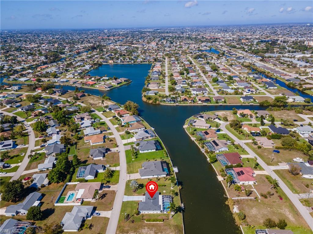 Aerial view of property and surrounding area featuring nearby suburban area and a large body of water