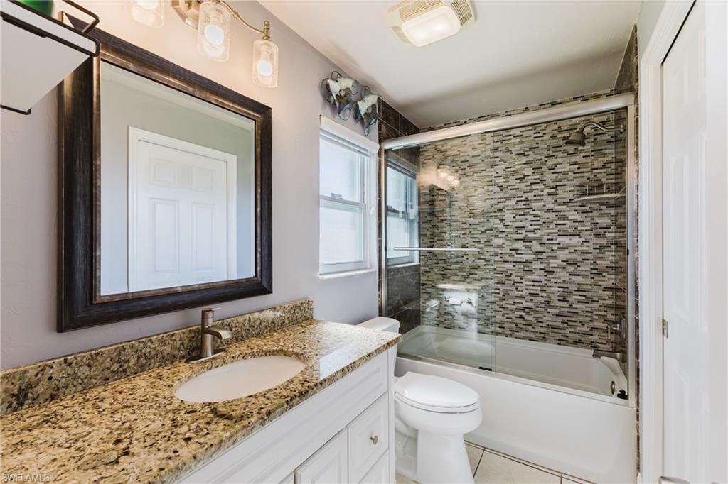 Full bathroom featuring vanity, shower / bath combination with glass door, and light tile patterned floors