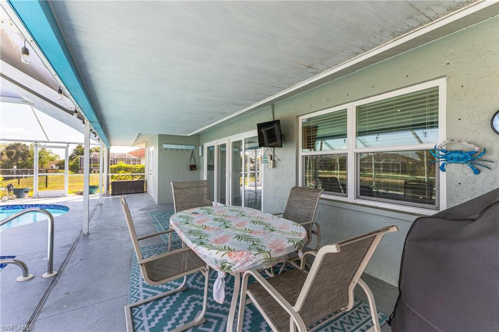 View of patio with an outdoor pool, glass enclosure, outdoor dining area, and a sunroom