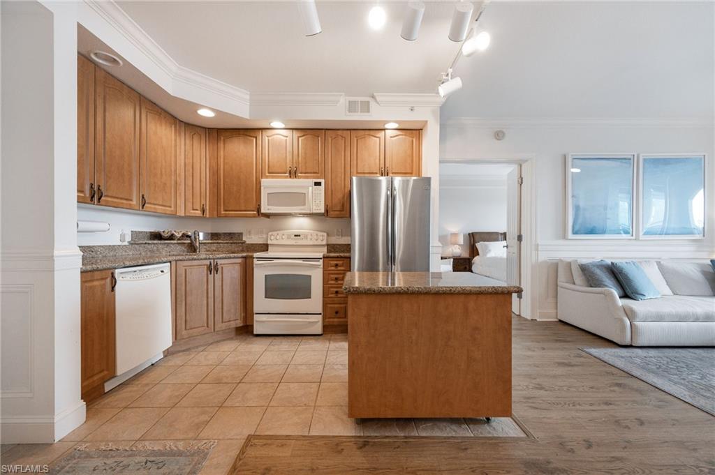 Kitchen with white appliances, ornamental molding, light hardwood / wood-style floors, and sink