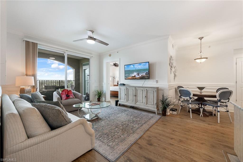 Living room with wood-type flooring, ornamental molding, and ceiling fan