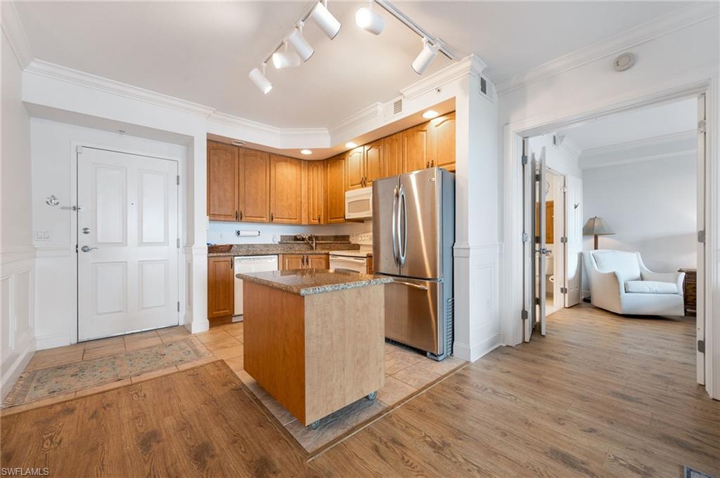 Kitchen with sink, ornamental molding, a center island, white appliances, and light hardwood / wood-style flooring