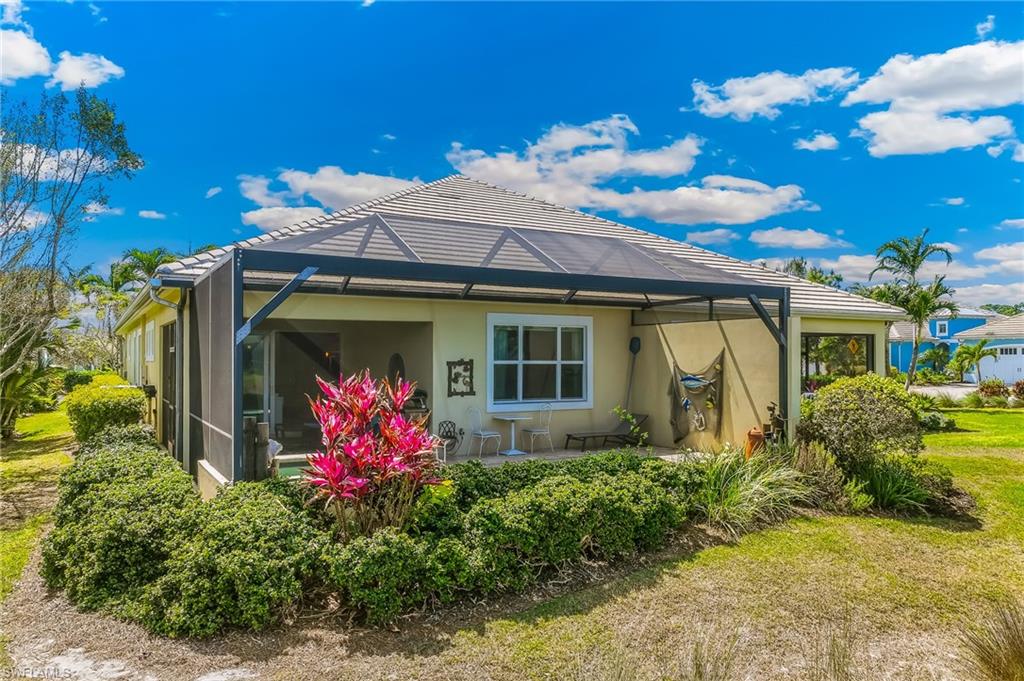 Rear view of house featuring a sunroom, stucco siding, a lanai, and a lawn
