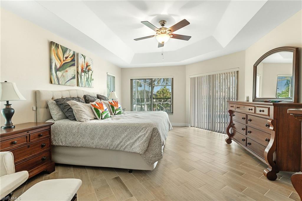 Bedroom featuring a tray ceiling, wood tiled floors, and a ceiling fan
