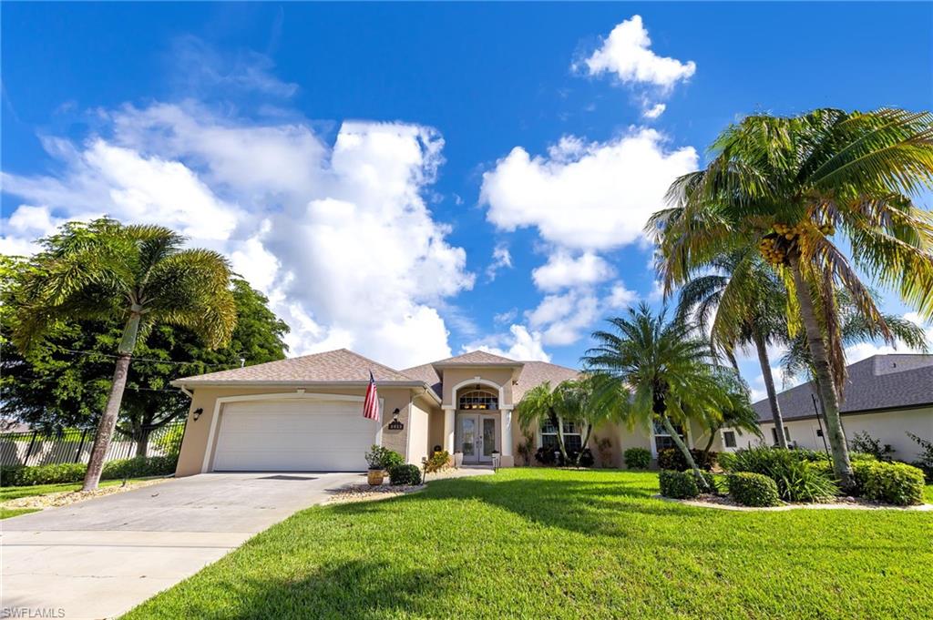 View of front of home featuring stucco siding, driveway, a garage, and a front lawn