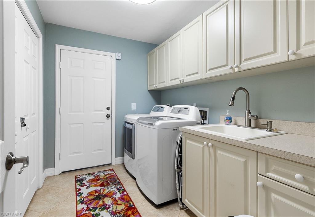 Laundry area with cabinet space, light tile patterned floors, and independent washer and dryer