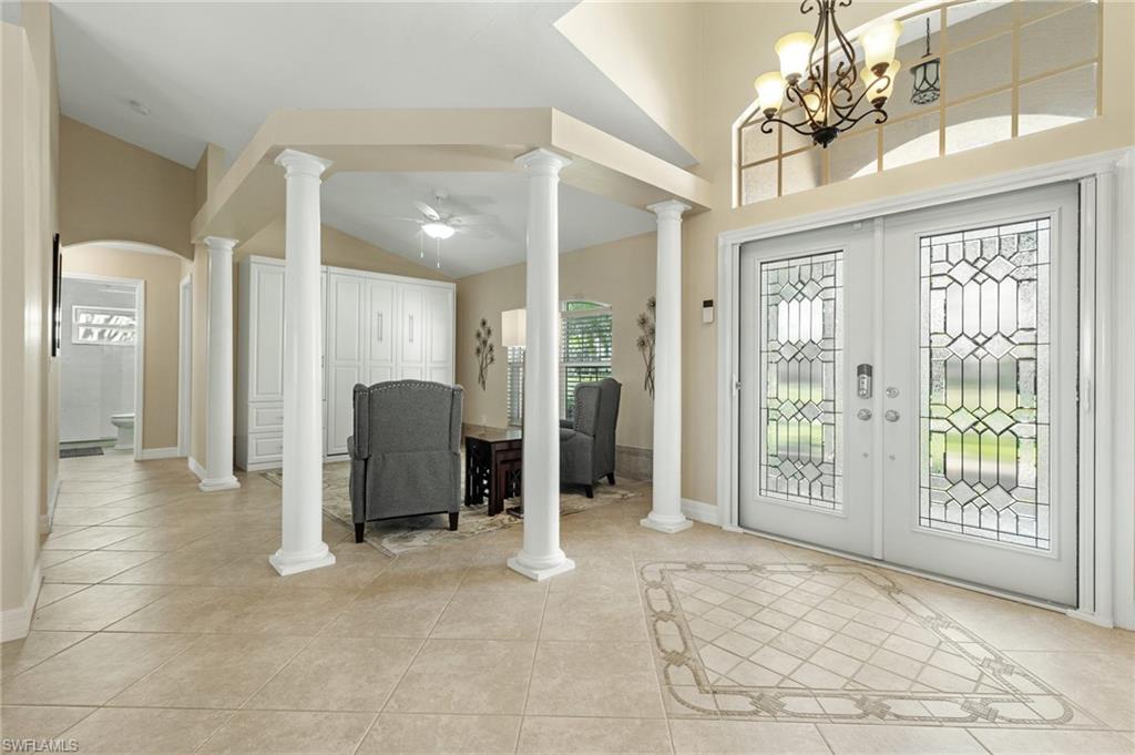 Entryway featuring light tile patterned floors, a ceiling fan, high vaulted ceiling, french doors, and a chandelier