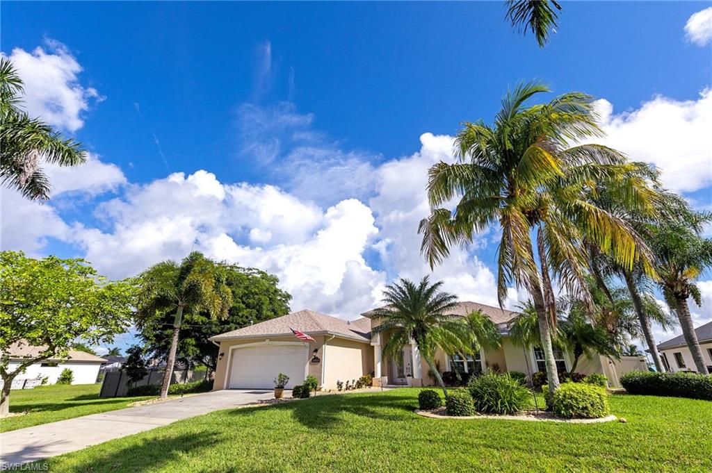 View of front facade with a front yard, driveway, and a garage