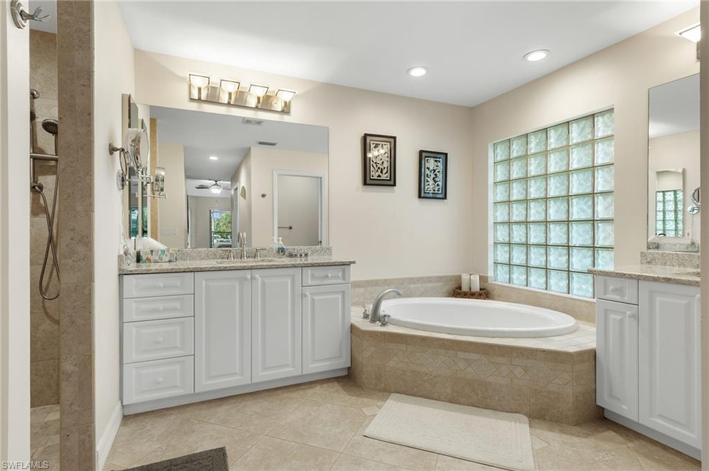 Bathroom with a bath, two vanities, a walk in shower, light tile patterned flooring, and recessed lighting