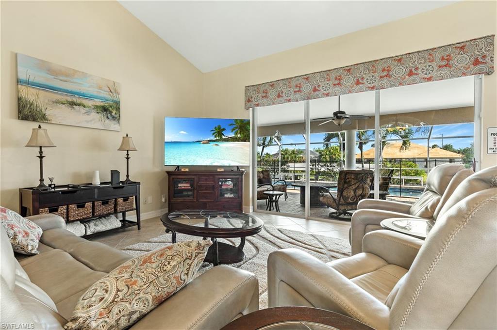 Living area featuring tile patterned floors, high vaulted ceiling, a sunroom, and a ceiling fan