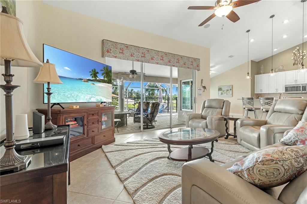 Living area with a ceiling fan, light tile patterned floors, high vaulted ceiling, and a sunroom