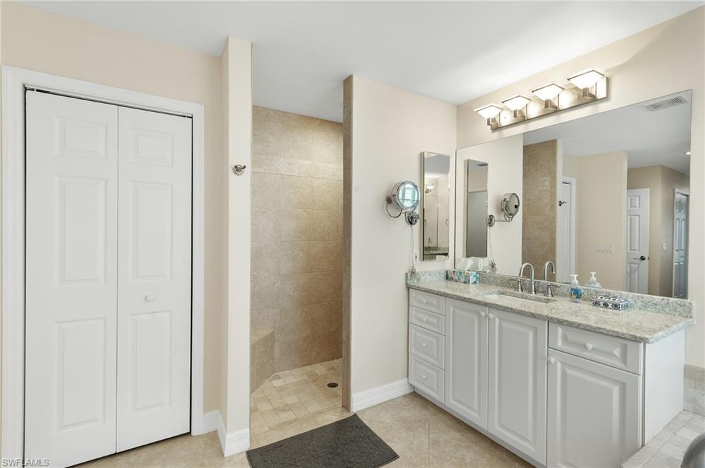 Bathroom featuring a closet, vanity, a shower stall, and light tile patterned floors