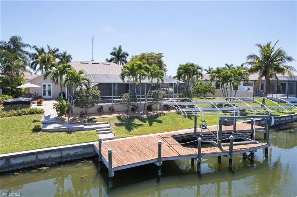 Dock area featuring a water view, boat lift, an oversized yard, and screen enclosure around pool.