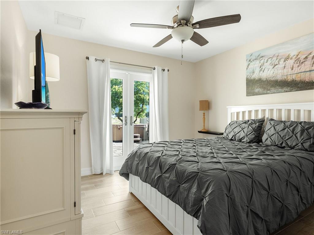 Bedroom with wood tiled floors, access to outside, ceiling fan, and french doors
