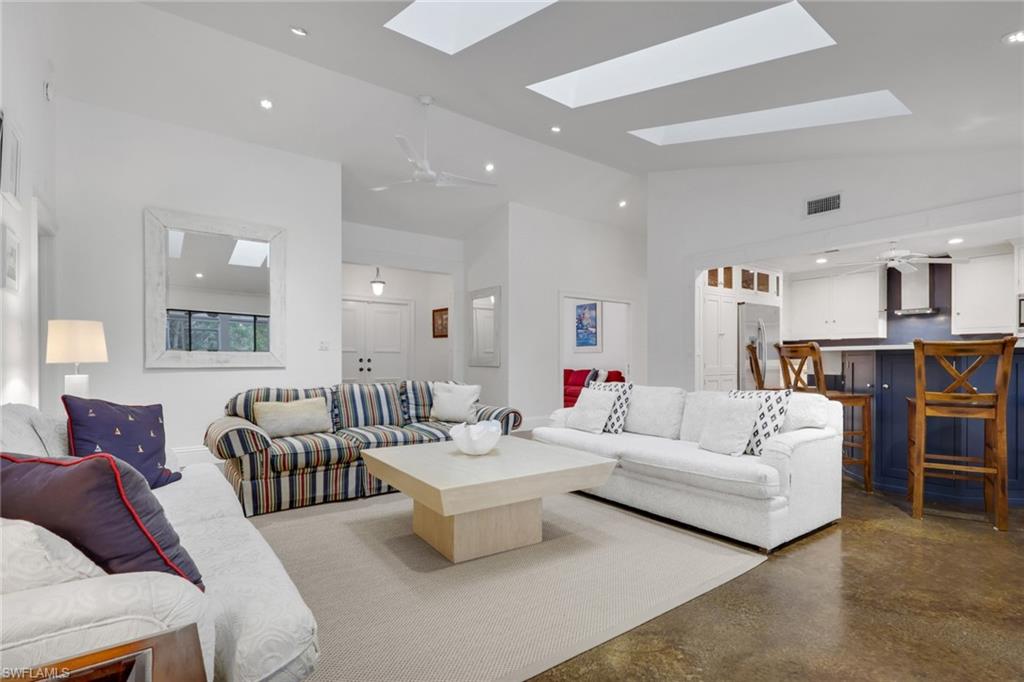 Living area featuring ceiling fan, concrete flooring, recessed lighting, lofted ceiling, and a skylight