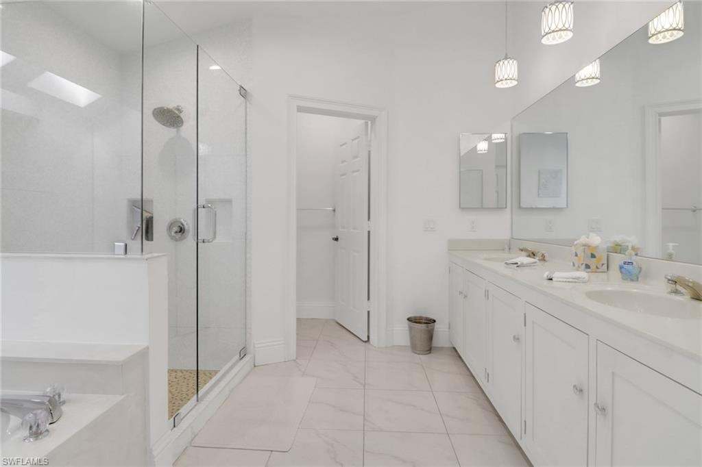 Primary Bath, custom lighting, newer wood cabinets, wonderful marble tile flooring
